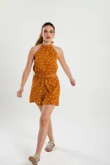 Mono corto color ocre con estampado floral en tonos rosados, con cuello halter y lazo en la cintura.