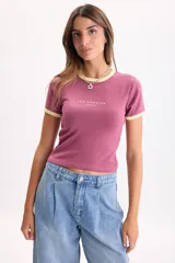 Remera manga corta de rib color bordó, con cuello redondo y ribetes en color amarillo claro en cuello y mangas. Cuenta con estampa frontal centrada con el texto "LOS ANGELES CALIFORNIA" en tono amarillo.