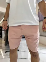 Bermuda de jogging color beige, con bolsillos laterales y estampa con texto blanco en la pierna izquierda.