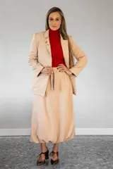 Pollera midi de corte amplio y diseño tipo bomber, con cintura alta y ajuste mediante lazo, confeccionada en tela de color beige.