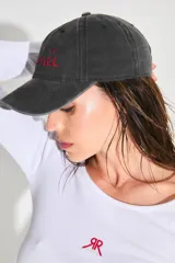 Gorra de gabardina negra con efecto lavado vintage, logo bordado en rojo en el frente y corazón bordado en la parte trasera.