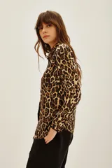 Camisa de corte clásico con cuello camisero y cierre frontal de botones, confeccionada en tela fluida con estampado animal print de leopardo.