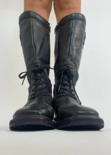 Botas de cuero negras de caña alta, con cordones y cierre lateral.