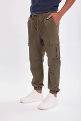 Pantalón cargo estilo jogger color verde militar, con cintura elástica ajustable con cordón y puños elásticos en los tobillos. Presenta bolsillos cargo en los laterales de las piernas.