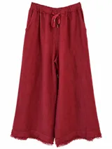 Pantalón de lino color bordó, de corte ancho y relajado, con cintura elástica con cordón de ajuste y detalles de flecos en el ruedo.
