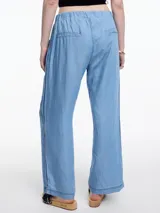 Pantalón de pierna recta y calce relajado, confeccionado en denim de lyocell con caída fluida. Presenta cintura elástica, bolsillos laterales y una pestaña lateral decorativa que recorre la prenda desde la cintura hasta el ruedo.