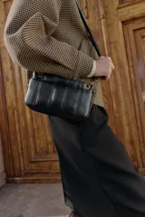 Bandolera mini de diseño acolchado con pespuntes verticales. Cuenta con doble compartimento, uno con cierre imantado y otro con cremallera, además de un bolsillo frontal con cierre imantado. Incluye asa regulable con detalle de cadena metálica.