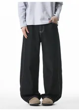 Pantalón de jean negro de corte muy ancho (baggy), con costuras exteriores en hilo blanco contrastante.
