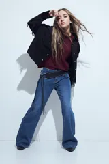 Campera negra de estilo western con flecos en las mangas, corte cropped, bolsillos frontales y cierre con botones metálicos.