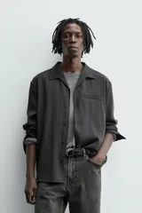 Camisa de manga larga color negro, confeccionada en tejido fluido con mezcla de viscosa. Presenta cuello bowling, bolsillo de vivo en el pecho y efecto lavado.