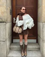 Buzo tejido de punto color crudo con diseño off-shoulder, textura acanalada y calce relajado.