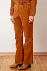 Pantalón de cuero ovino italiano color tostado, con corte recto y tiro medio. Presenta diseño de cinco bolsillos, cierre frontal con botón y costuras reforzadas.