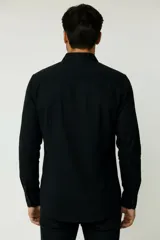 Camisa de corte holgado, color blanco, con cuello clásico, cierre frontal de botones y bolsillo en el pecho.