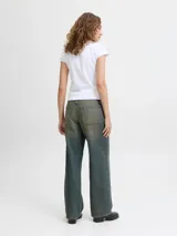 Jean de denim para mujer, de tiro bajo y corte loose fit con pernera amplia. Presenta un lavado con efecto desgastado de tono amarillento, cierre frontal con botón y cinco bolsillos clásicos.