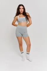 Conjunto deportivo compuesto por un top y un short de tiro alto en color gris. El top presenta breteles blancos y logo estampado en el frente, mientras que el short cuenta con costuras laterales en contraste blanco.