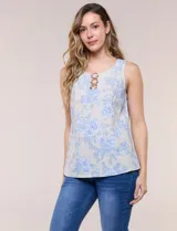 Blusa de lino y rayón color beige con estampado floral en tonos celestes, sin mangas, con escote redondo y detalle de tres aros metálicos plateados entrelazados en el frente.