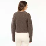 Sweater de punto con diseño trenzado, cuello redondo y mangas largas, de corte holgado y textura suave.