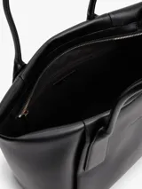 Cartera tote negra Tommy Hilfiger de acabado liso, con dos asas superiores y cierre de cremallera. Incluye un compartimento principal, un bolsillo interior con cremallera y logo metálico en relieve en la parte delantera.
