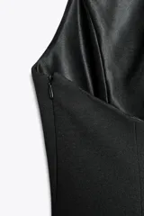 Top rosa claro, entallado, con cuello halter que se abrocha en la nuca y espalda descubierta. El bajo tiene un corte peplum acampanado.