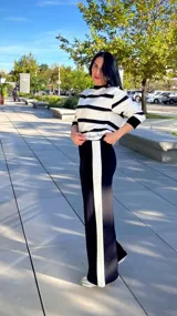 Pantalon de corte wide leg color negro con una franja vertical blanca lateral. Presenta un diseño de tiro alto y silueta fluida.