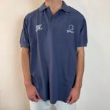 Chomba azul de piqué con cuello clásico y manga corta. Presenta bordados blancos con motivos de golf en el pecho.