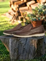 Mocasines de cuero color marrón con suela de goma blanca, diseño tipo náutico con costuras reforzadas en la puntera.