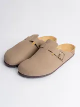 Zueco tipo mule color beige con tira ajustable lateral con hebilla metálica y suela de corcho con base de goma.