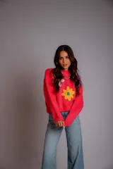 Buzo de punto color fucsia, con cuello redondo, manga larga y bordado de flores en amarillo y azul en el frente.