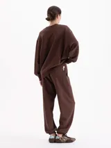 Pantalón tipo jogging de silueta amplia y largo al tobillo, confeccionado en algodón. Cuenta con cintura elastizada, cordón ajustable y bolsillos laterales. Su diseño incluye elásticos en las botamangas que permiten regular el ajuste.