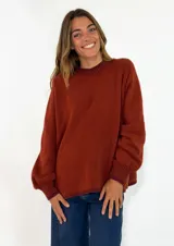 Sweater de tejido de punto color terracota, con cuello redondo, mangas largas abullonadas y puños acanalados.