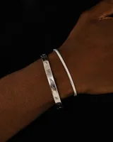 Pulsera rígida plateada con diseño trenzado.
