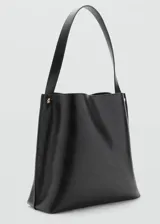 Bolso tipo saca de diseño minimalista en color negro, con asa de hombro fija y detalles de botones metálicos dorados en los laterales. Cuenta con cierre de mosquetón y forro interior.