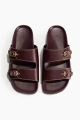 Sandalias H&M color bordó, de diseño abierto con dos tiras anchas en el empeine, cada una equipada con una hebilla metálica dorada y costuras pespunteadas en contraste. Plantilla anatómica.