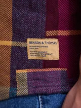 Camisa de manga larga en color azul noche con un patrón de cuadros finos en tonos rojos y verdes. Presenta cuello clásico, cierre frontal con botones y un bolsillo en el pecho con solapa.