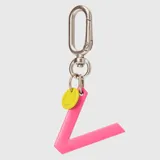 Llavero con dije en forma de letra A color rosado y pequeño dije circular amarillo con logo de la marca grabado. Incluye gancho metálico tipo mosquetón.