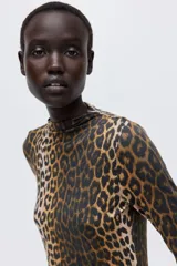Top de punto con cuello alto y manga larga, con diseño de estampado de leopardo y terminaciones con remate sobrehilado en puños y bajo.