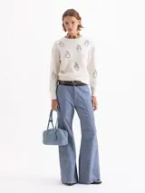 Sweater de tejido de punto gris con textura de pelo, cuello redondo y mangas largas. Presenta un bordado frontal de piedras brillantes con forma de flamas.