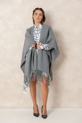 Ruana abierta de corte amplio y sin mangas, confeccionada en tejido de lanilla gris con detalle de flecos en el ruedo.