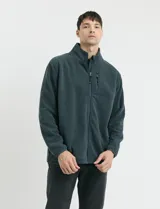 Campera de micropolar color verde oscuro, con cuello alto, cierre frontal completo, bolsillos laterales y un bolsillo con cierre en el pecho.