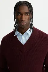 Buzo de punto acanalado en color bordó, con cuello en V y detalles de rayas blancas en contraste en los puños y el ruedo. Presenta un corte boxy que ofrece una silueta amplia y estructurada.