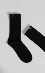 Medias negras de corte alto y tejido acanalado, confeccionadas en una mezcla de algodón y spandex, con una pequeña etiqueta distintiva con forma de tijera en el borde superior.