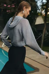 Sudadera de punto con hilo metalizado color gris, con capucha, manga larga y cierre frontal con cremallera.