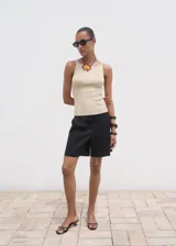 Top de punto fino color beige, con cuello barco, tirantes finos y diseño entallado al cuerpo.