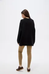 Sweater de punto negro, con cuello redondo a la base, manga larga y diseño holgado.