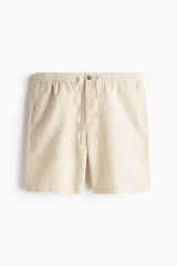 Short de mezcla de algodón y lino color beige, con cintura elástica con cordón de ajuste, botón frontal, bolsillos laterales y corte estándar.