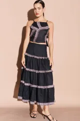 Falda larga negra de lino con volados en distintos niveles, cada uno con un borde brillante.