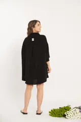 Camisa negra oversize de manga larga con cuello camisero y cierre frontal con botones.