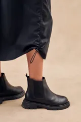 Falda midi negra estilo parachute, con cintura elástica, bolsillos laterales tipo cargo y cordones ajustables en el ruedo.