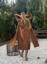 Tapado marrón de cuero con corte a la rodilla, mangas largas y aberturas laterales.