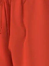Short de baño Tommy Hilfiger color naranja, con cintura elástica ajustable mediante cordón. Presenta un diseño liso con el logo de la marca estampado verticalmente en el lateral izquierdo.